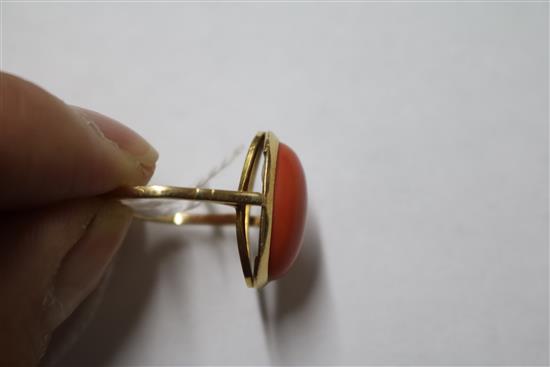 A yellow metal and oval cabochon coral ring, size R.